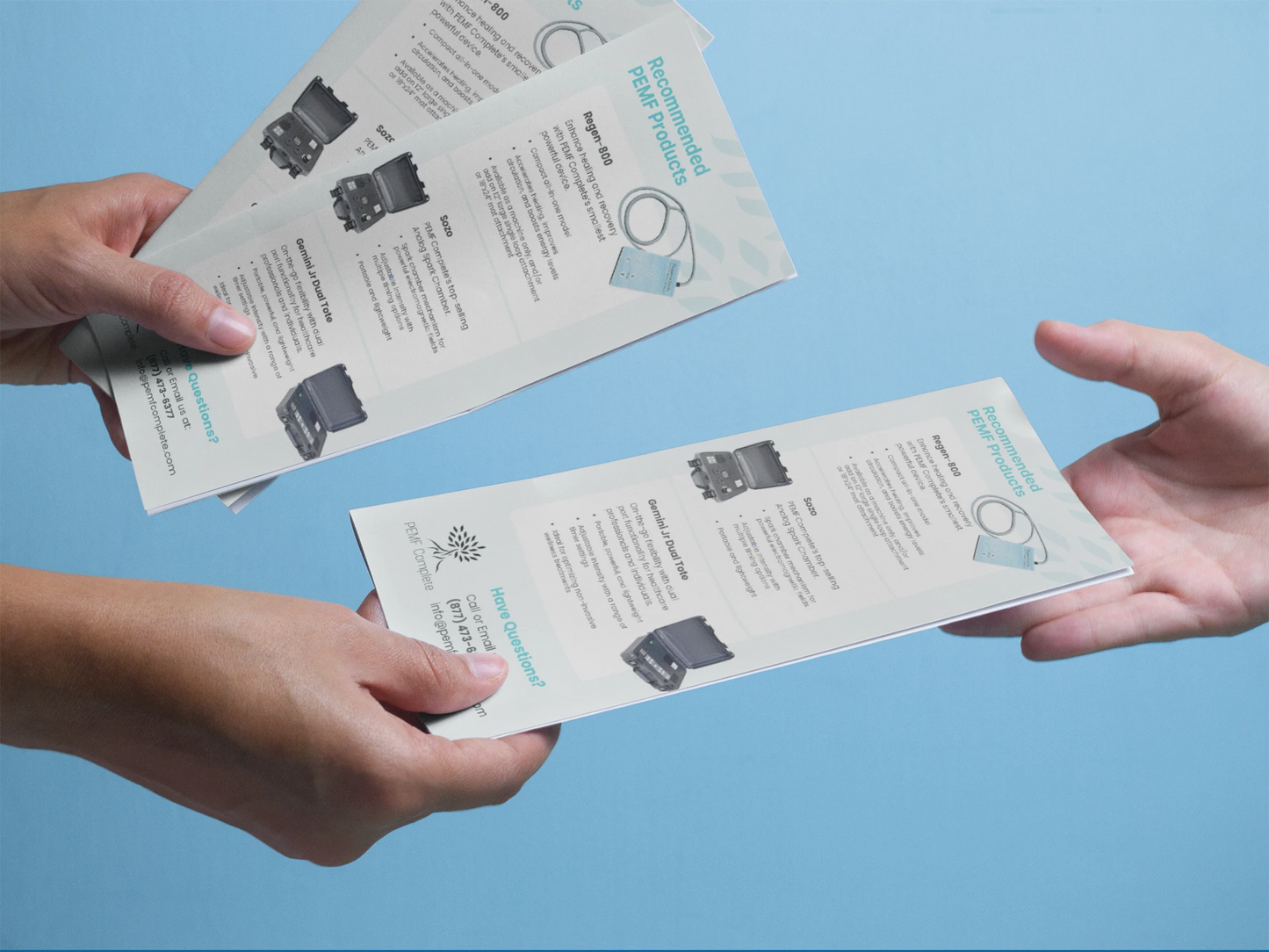 Two hands holding printed leaflets against a blue background