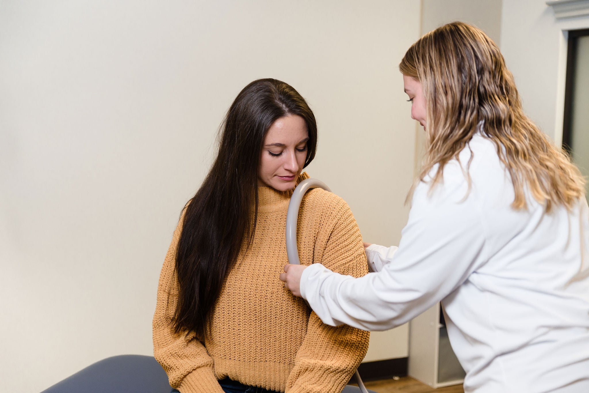 Placing a PEMF loop on a woman's shoulder