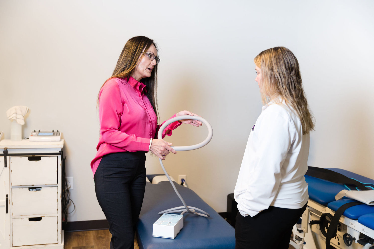 Owner Stephanie explains the use of a PEMF device and attachment to another woman