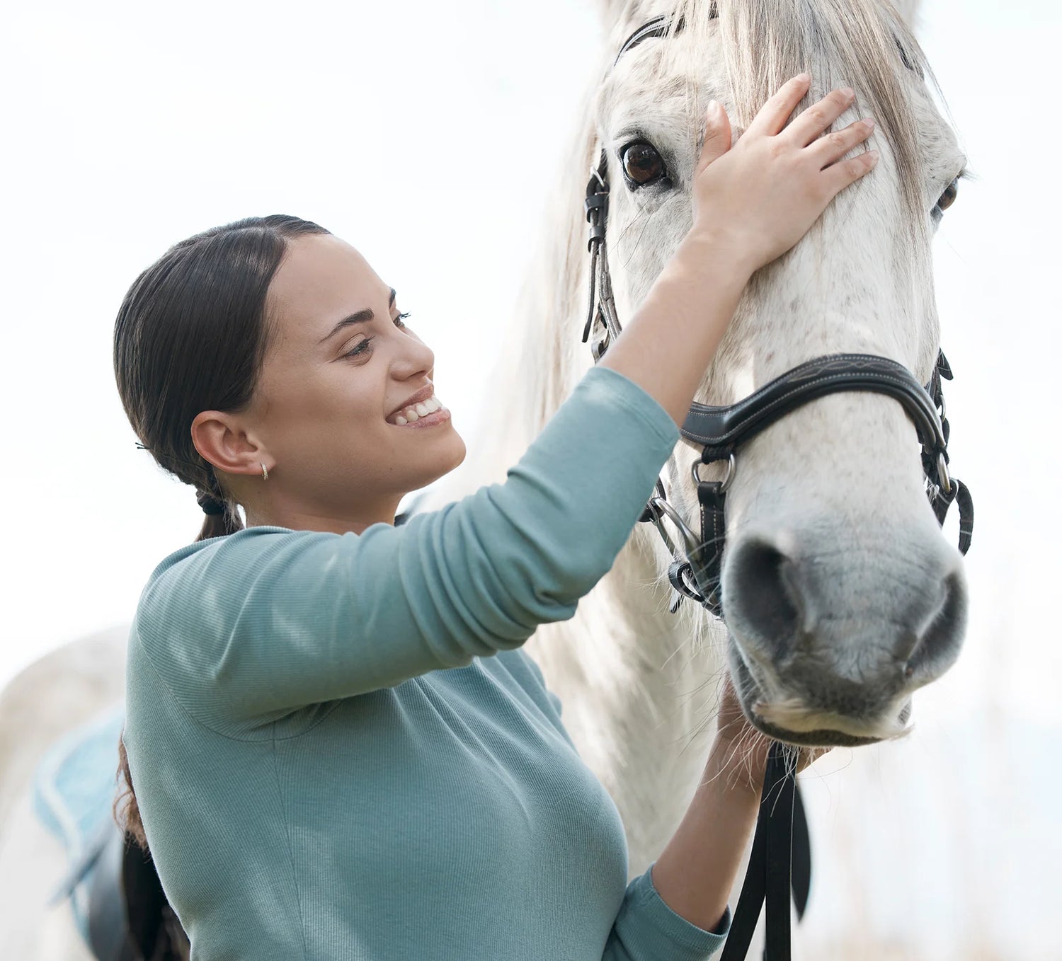 Woman smiling and petting a white horse